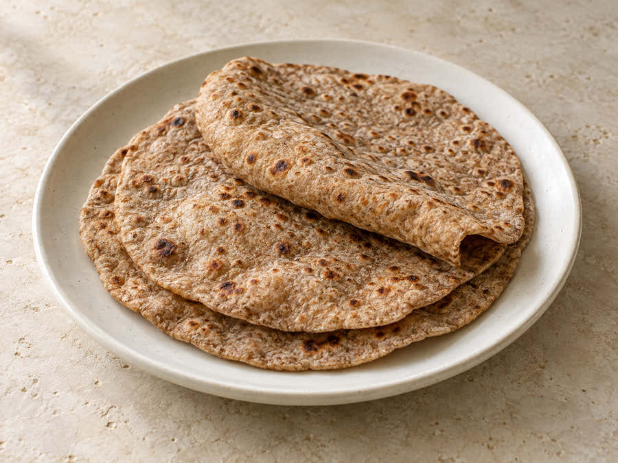 Wholegrain black wheat chapatis on an ivory plate